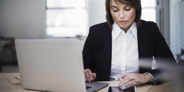 A businesswoman studies her documents intently in a white office.