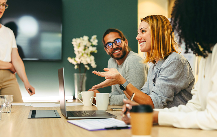 Mitarbeitende sitzten lachend am Meetingtisch