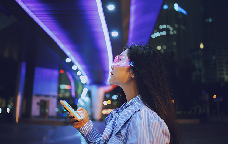 Young woman standing under a light with her cell phone and safety glasses