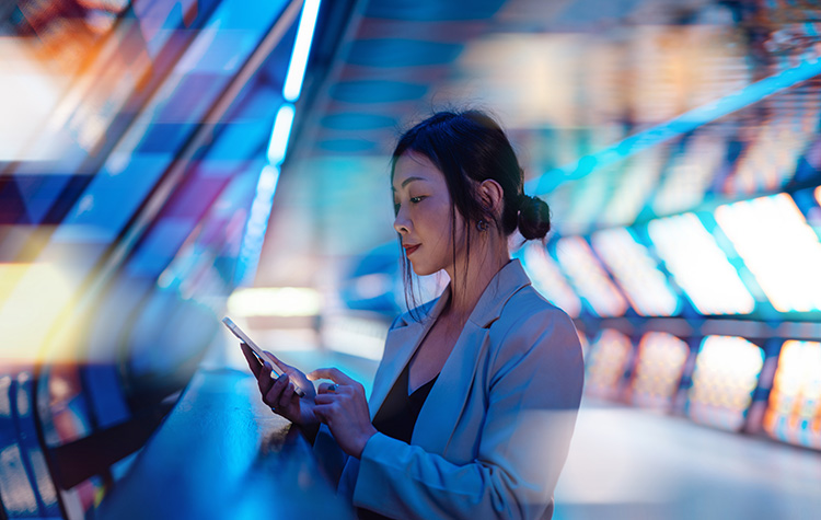 Junge Frau steht in futuristischem Büro und arbeitet an ihrem Handy