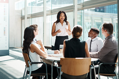 Junge Gruppe Arbeitnehmender sitzt im Meeting in der Sonne