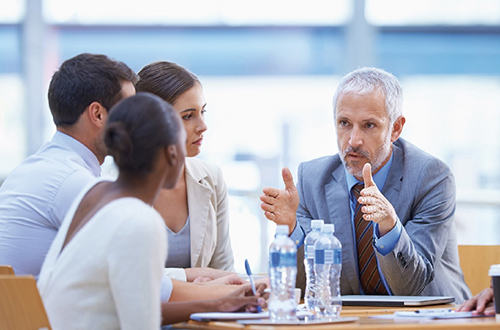 Älterer Geschäftsmann erklärt jüngeren Kollegen in einem Meeting etwas