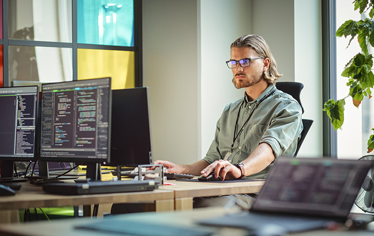 Junger Mitarbeiter arbeitet im Büro an Code