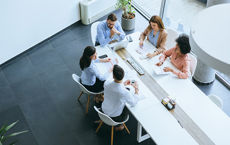 Sales- und Marketing-Mitarbeitende sitzen zusammen an einem großen Tisch