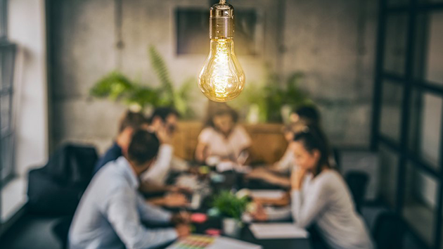 Verschiedenste Menschen sitzen am Tisch und sprechen über Unternehmenskultur