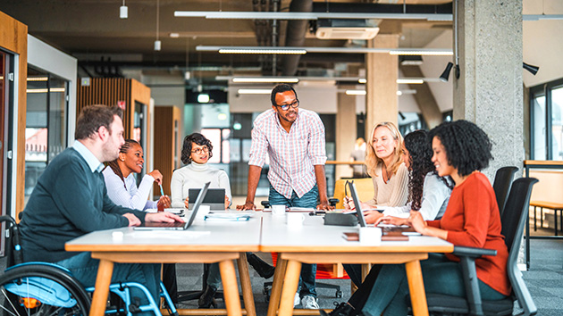 Diverses Team sitzt zusammen am Tisch und arbeiten