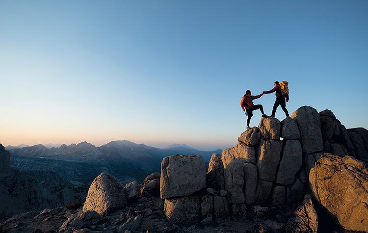 Bergsteiger helfen sich gegenseitig auf die Spitze